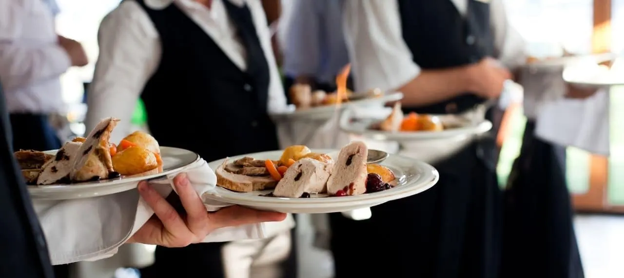 Waitstaff carrying plated meals at a wedding reception