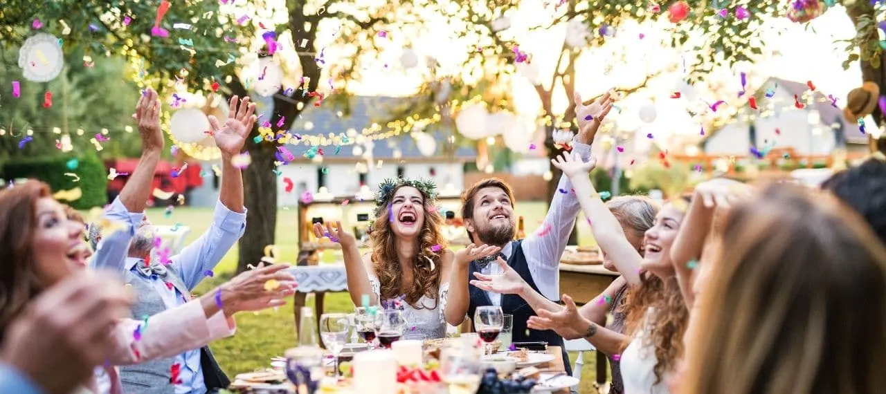 Wedding guests celebrating with confetti at an outdoor reception table