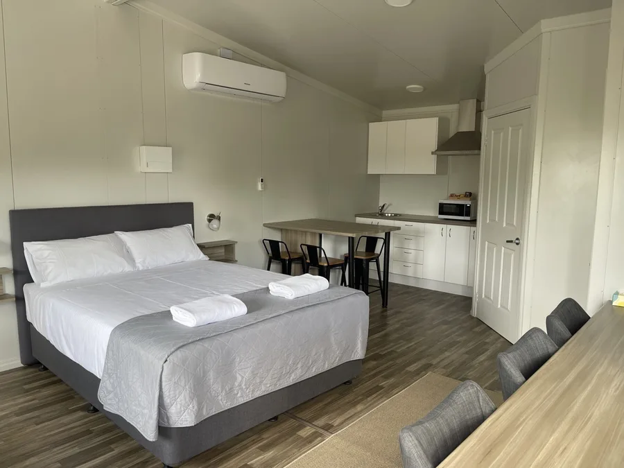 Self-contained studio room at Cornwall House with a queen bed, kitchenette, dining table and air conditioning