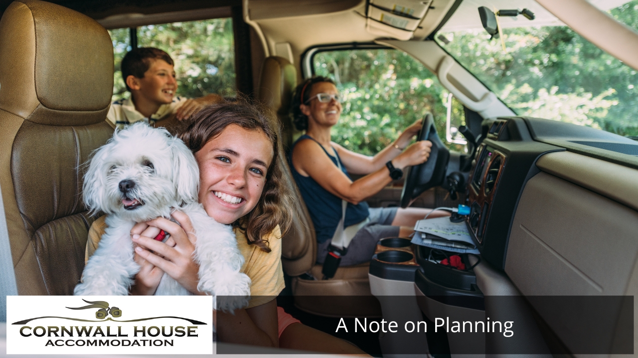 A smiling girl holding a small white dog in a vehicle with a woman driving and a boy in the back